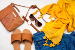 a purse sunglasses a watch a pair of sandals and a scarf are laid out on a table