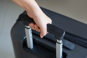 a woman 's hand is holding the handle of a black suitcase
