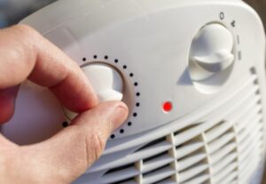 Man's,Hand,Adjusts,The,Temperature,Of,The,Electric,Fan,Heater