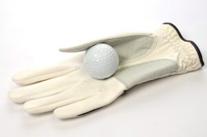 a white golf glove is holding a white golf ball